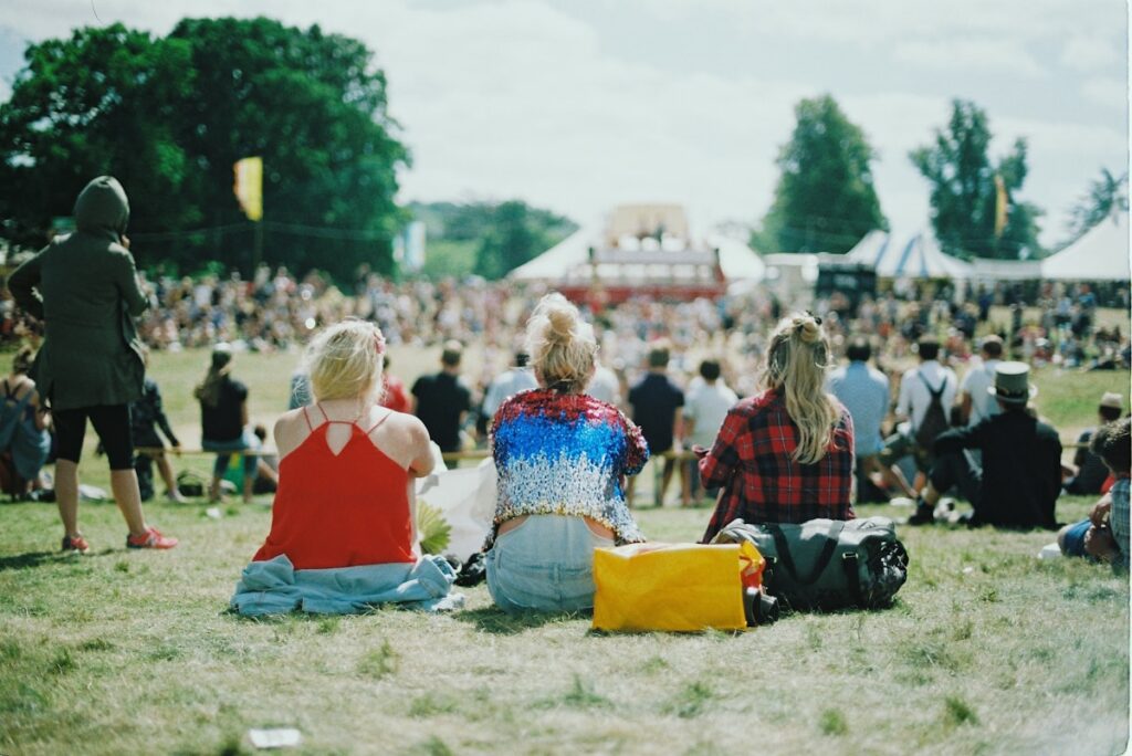 A group of people on a grass field on a sunny festival day