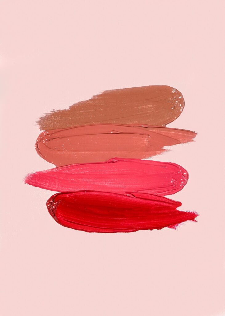 Open lipstick tubes on a soft pink surface in late-summer light