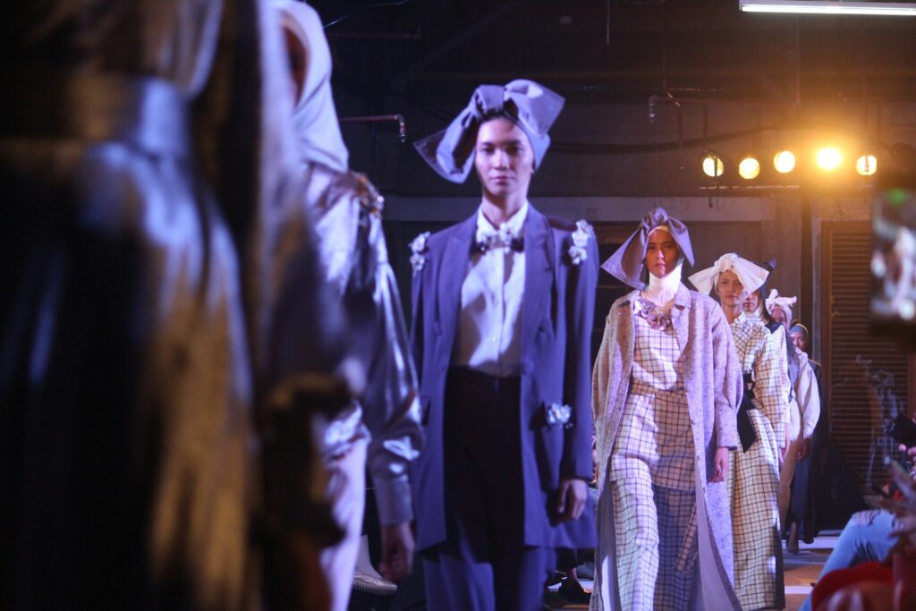 A row of models walking a fashion show in coordinated dresses