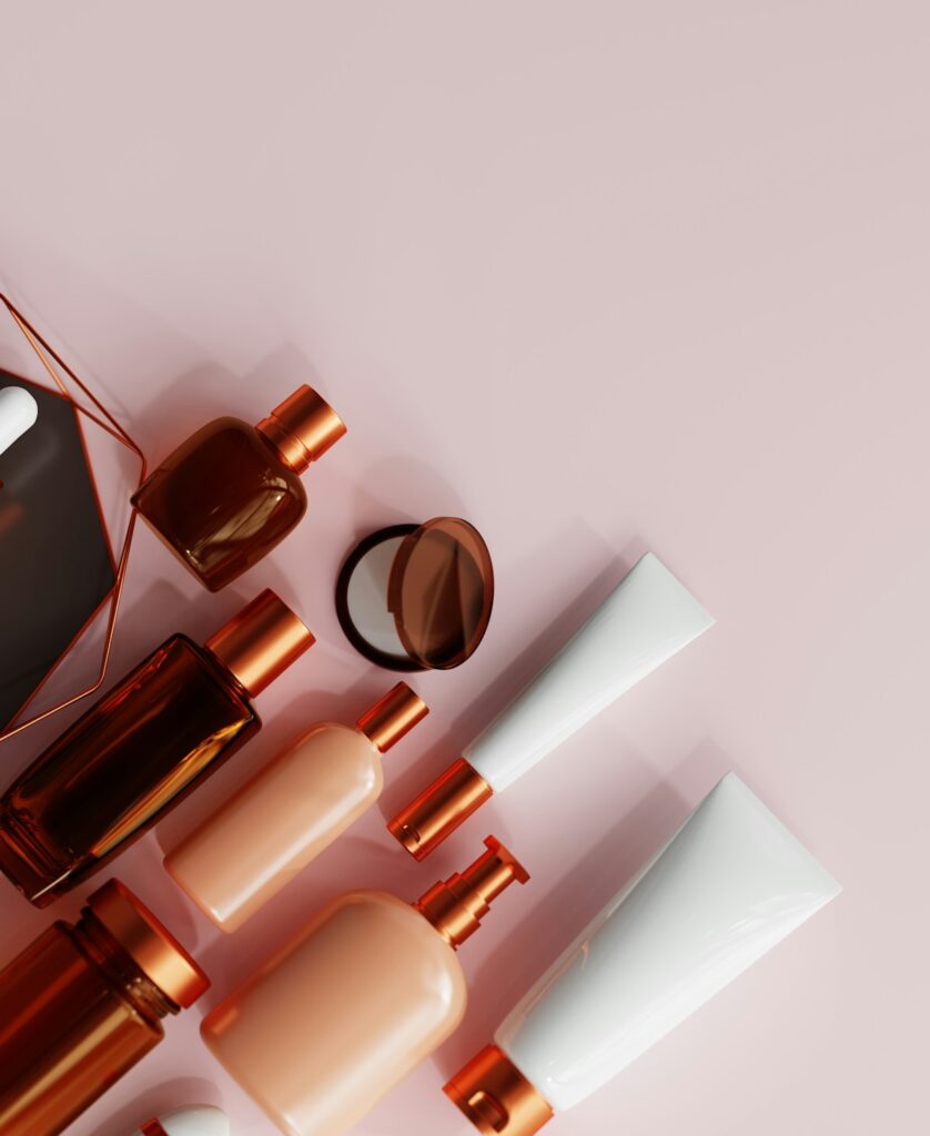 An assortment of makeup products laid out on a pink background