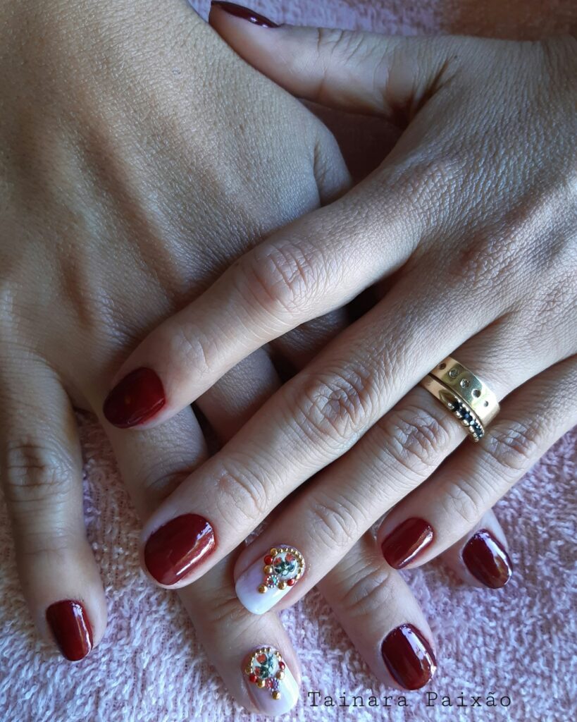Hands with deep burgundy and gold-accented manicure