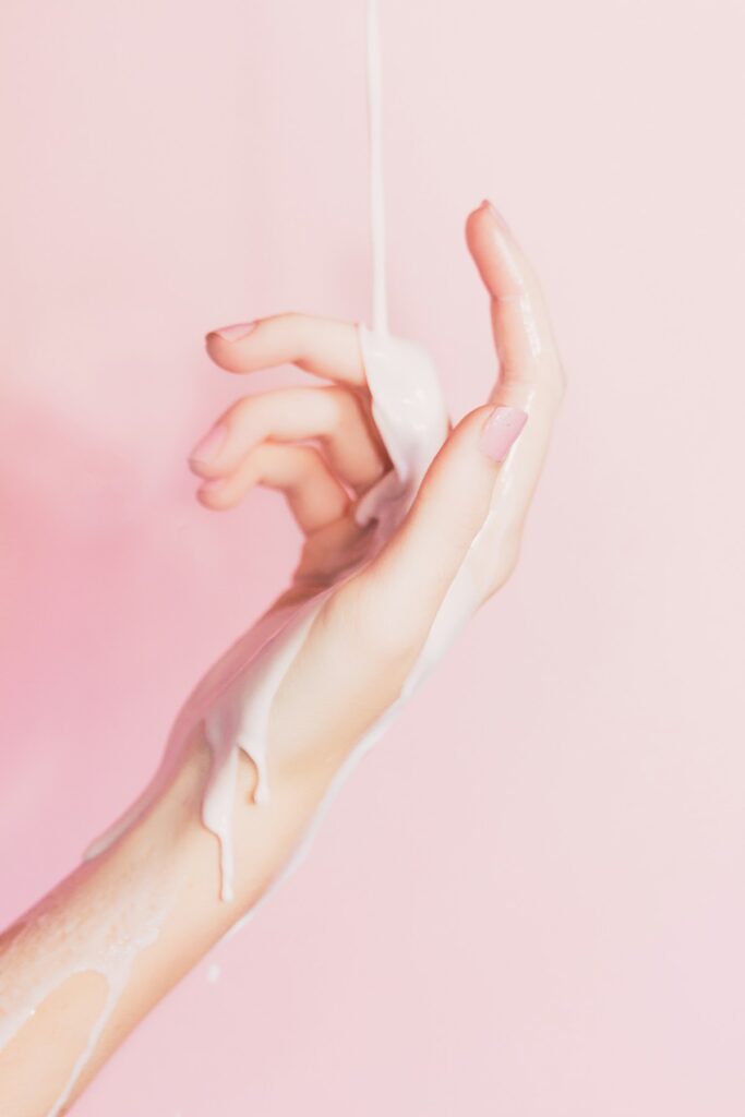 A hand holding a small bottle of lotion
