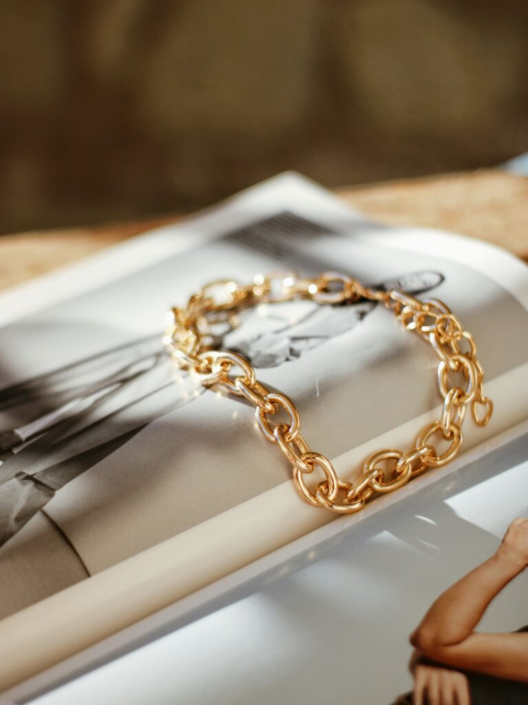 A gold chain bracelet resting on the cover of a magazine