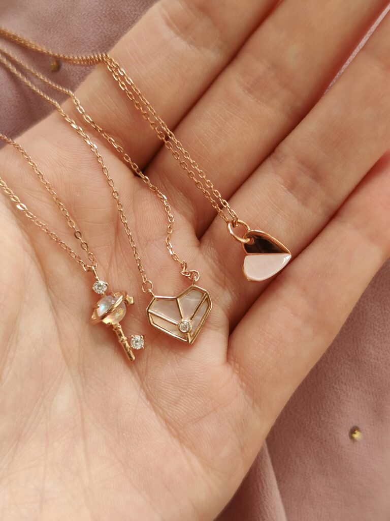 A hand holding several delicate necklaces against a soft background