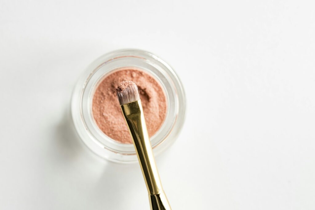 Pink blush powder with brown makeup brush on glass case