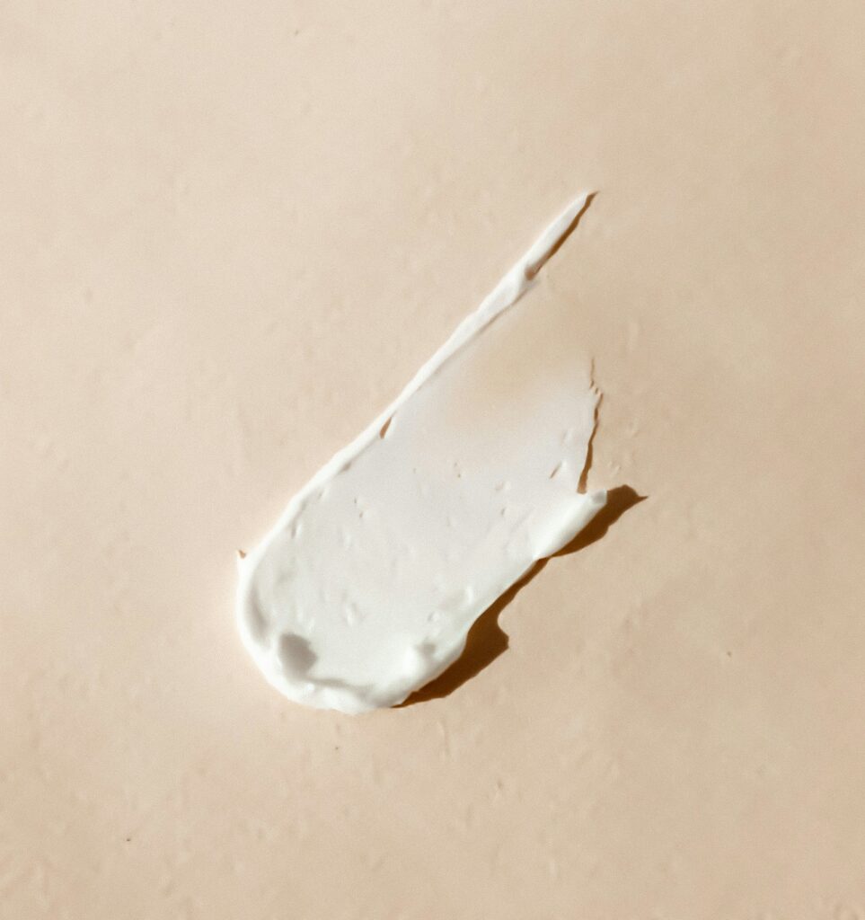 Summer sunscreen and after-sun balm arranged on a tile-and-grass surface