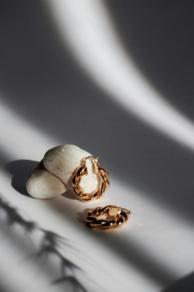 Stacked gold bracelets and a charm necklace on creamy linen