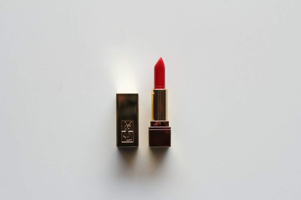 Red lipstick tube on a fall wooden surface