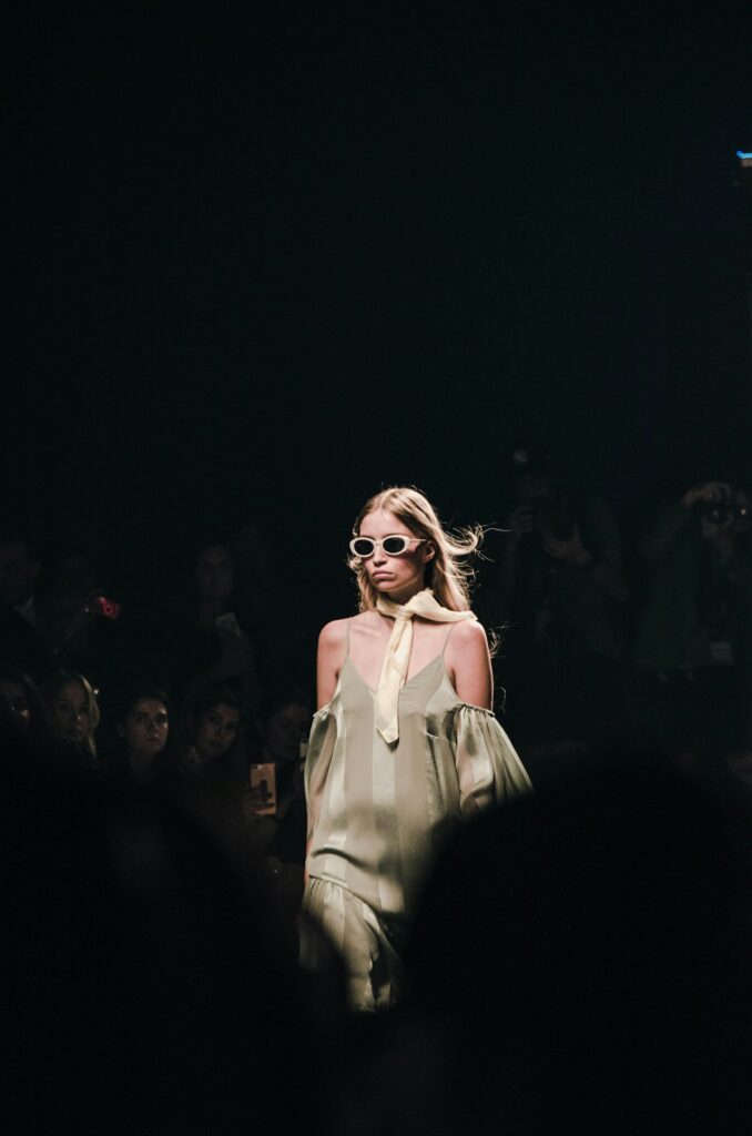 Models walking a fashion runway under bright lights