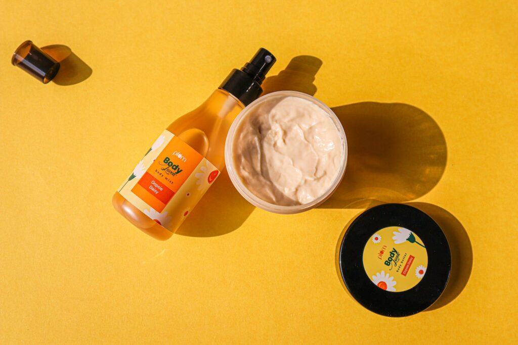 Body mist and body butter on a sunny yellow background — summer body care editorial